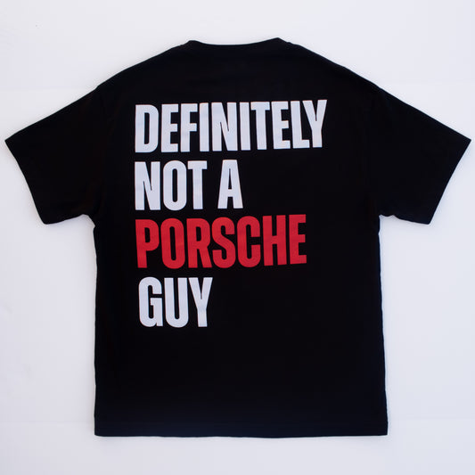 A black short-sleeve t-shirt shown from the back, featuring the text 'DEFINITELY NOT A PORSCHE GUY' printed in bold white and red letters.